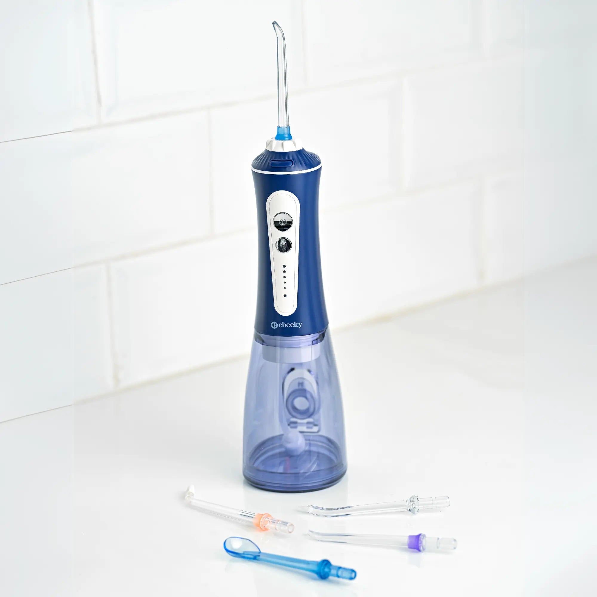 Blue and white dental water flosser with attachments on a white tiled bathroom floor.