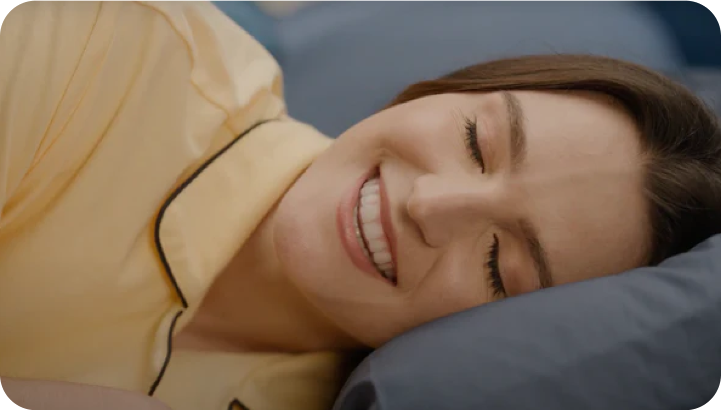 A woman lays in bed with a bright smile 2-Cheeky