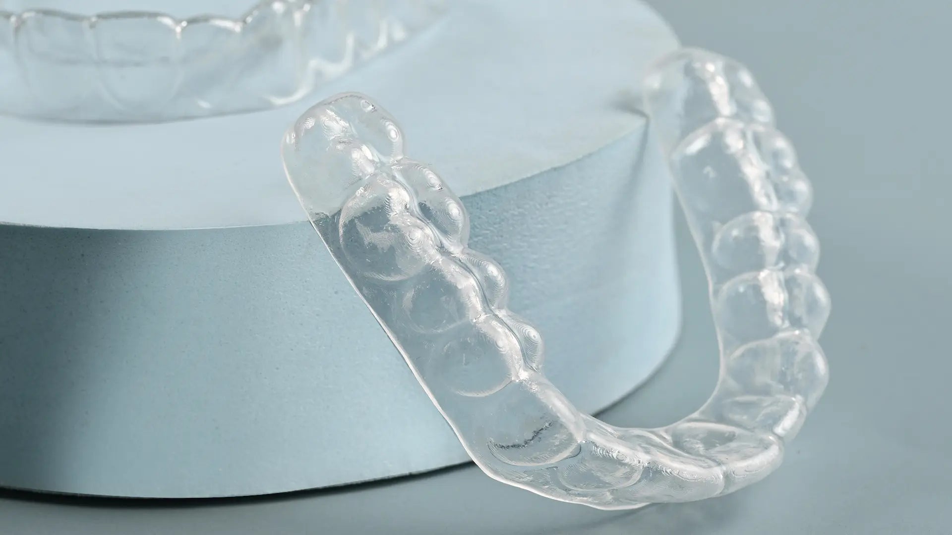 Clear dental aligners on a light blue background