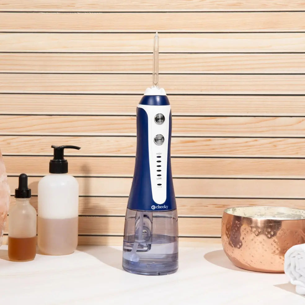 Blue and white dental water flosser on a bathroom counter with various items in the background.