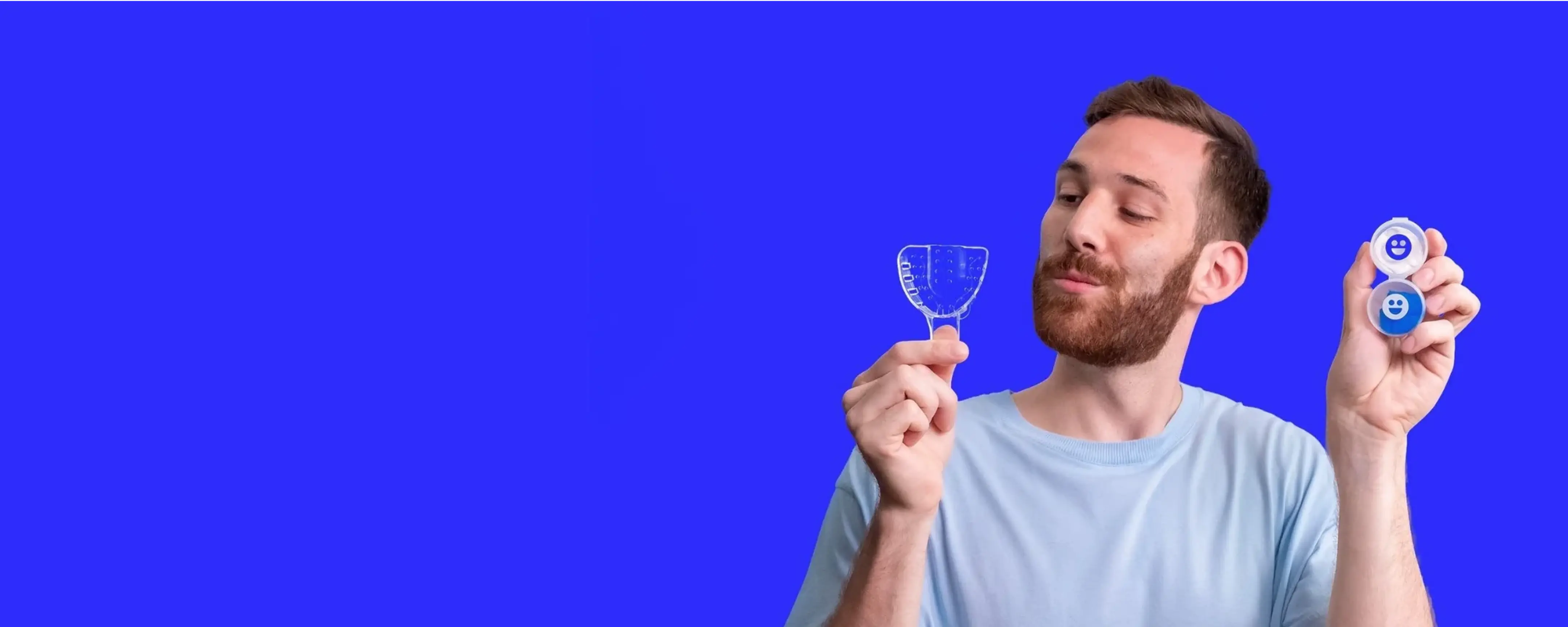 Man holding two dental floss products against a blue background