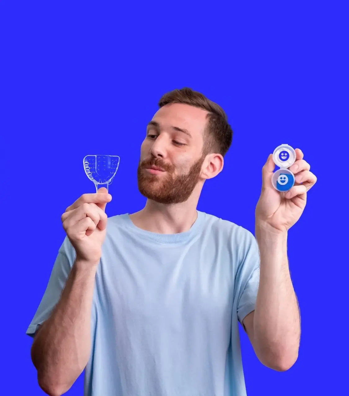 Man holding dental aligner and blue device against a blue background